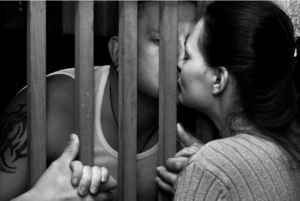 man and woman kissing between prison bars
