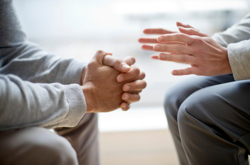 Two people sitting face to face with hands cropped